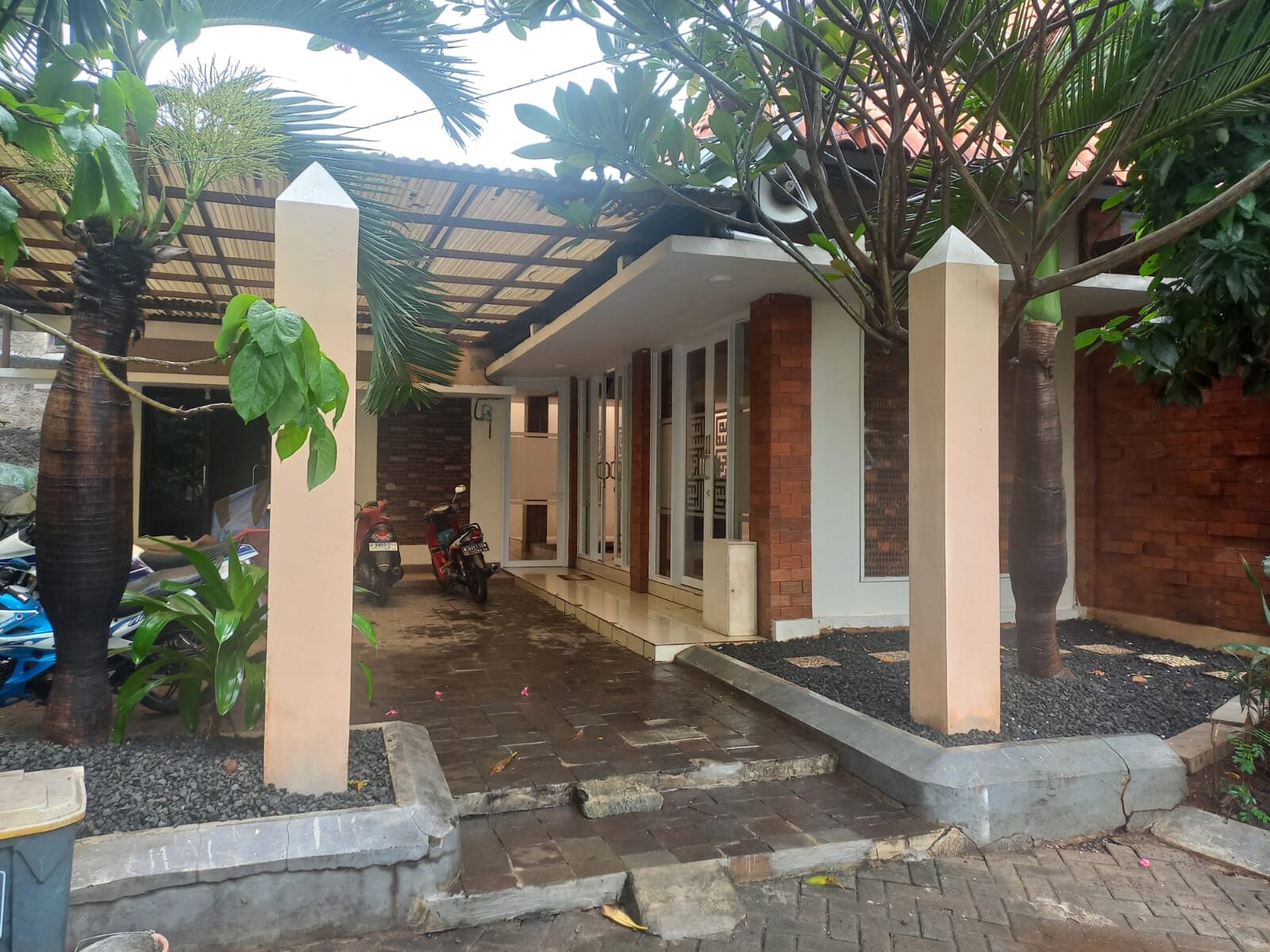 Teras depan Masjid Al Husna dengan pohon kamboja dan kanopi